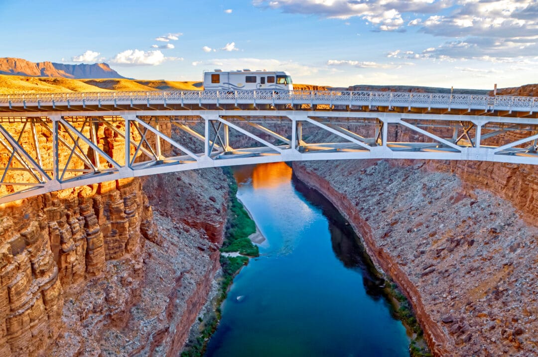 Motorhome crossing a high bridge over a river running through a canyon