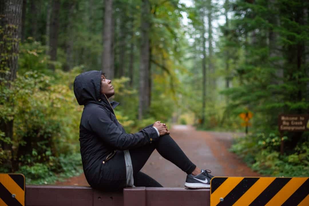 a woman sits on a barricade in a forest
