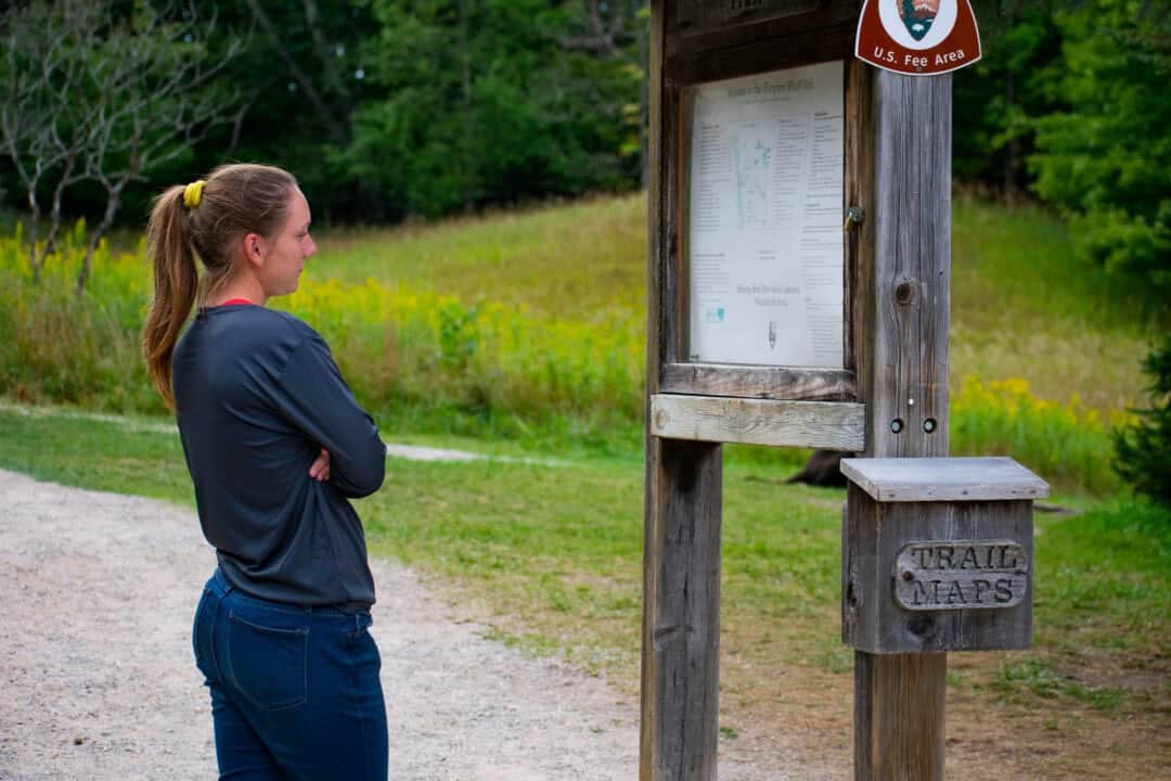 Young Caucasian women dressed casually studying map before hiking at Sleeping Bear Dunes National Lakeshore in Michigan.