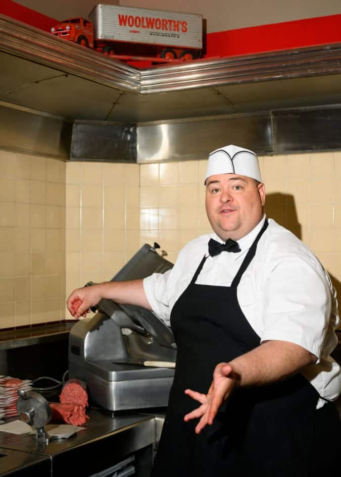 a man presses patties on a meat presser at woolworth's diner